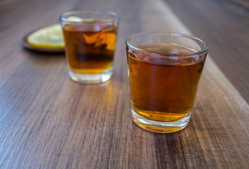 a two piles of whiskey and slices of lemon on a wooden background