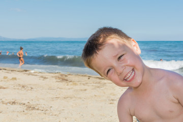 Fototapeta na wymiar a beautiful little boy posing on a beach by the sea 