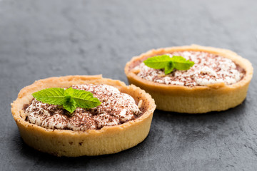 Mini  banoffee pie tarts isolated on black stone background