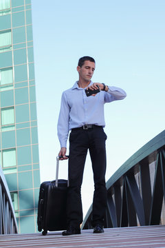 Businessman With Travel Luggage checking in time on wrist watch. Busines trip concept