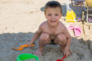 A nice little boy is playing on a beach in the sand