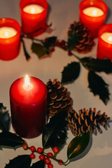 Christmas and New Year composition. Lit candles, fir cones and branch of holly