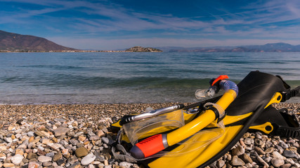 Flippers and snorkeling tube on sea shore