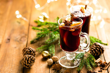 Christmas mulled red wine with spices and oranges on a wooden rustic table. Traditional hot drink at Christmas