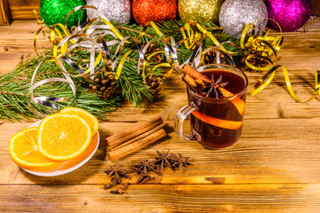 Cup of mulled wine with cinnamon, christmas decorations, sliced orange and fir tree branches on...