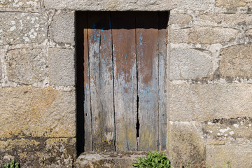 Puerta vieja de madera marrón en construcción de muro de piedra. A Limia, Ourense. Galicia, España.