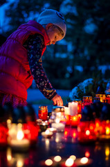 child during All Saints Day in the cemetery at night