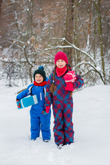Fototapeta na wymiar Happy children in a winter snow-covered forest with gift boxes.