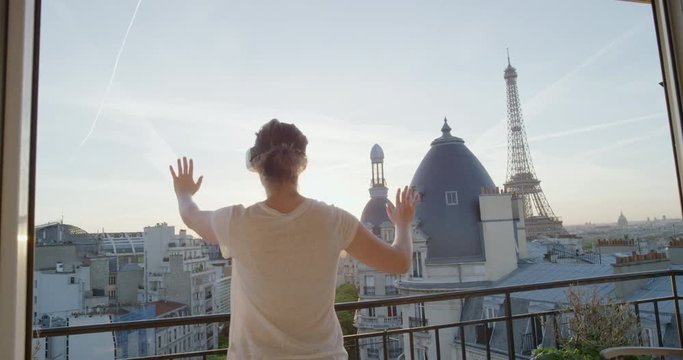 woman using virtual reality headset enjoying exploring online cyberspace experience on balcony in beautiful paris sunset eiffel tower