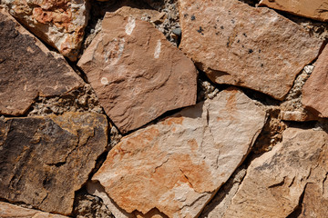 Part texture background made of natural stone, large pieces, yellow brown.