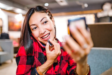 Modern business freelance woman doing make-up at lunch time in cafe