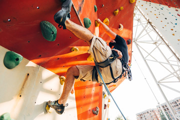 lead climbing, Sportive man climbs up on artificial rock wall