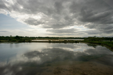 Fototapeta na wymiar un étang avec un ciel nuageux, menaçant et son reflet