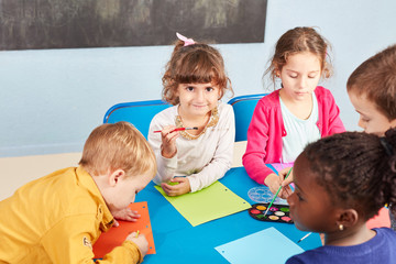 Fototapeta na wymiar Kinder malen mit Wasserfarbe und Pinsel