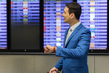 Businessman checking time in the airport, flight delay concept