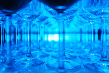 row of transparent clean wine glasses and champagne on a rack in a bar or restaurant prepared for guests of festive events. 