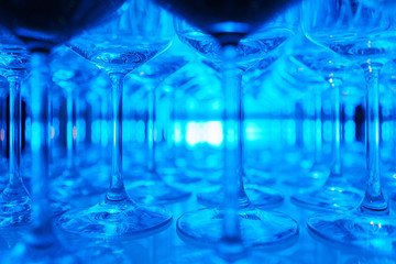 row of transparent clean wine glasses and champagne on a rack in a bar or restaurant prepared for...