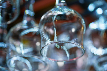 a wide transparent wine glass hangs on the background of other wine glasses in the bar. Close-up