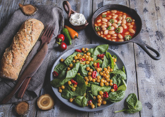 Chickpea and veggies salad with spinach leaves, healthy homemade vegan food, diet. white beans in tomato sauce