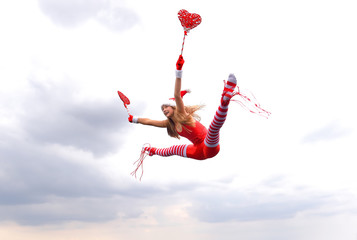 A young girl wearing a Santa Claus hat shows her happy  feelings for Christmas with jumping up in...