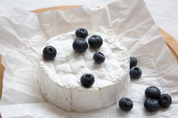 Camembert cheese in paper on bamboo board, close-up. Food for wine. Milk production.