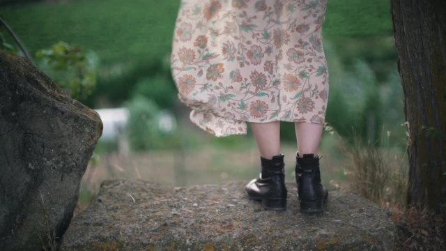 Woman stands on a stone, and her gentle, light dress develops in the wind