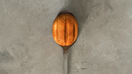 Close view of a cookies in the shape of walnut with condensed milk on vintage spoon on a concrete background