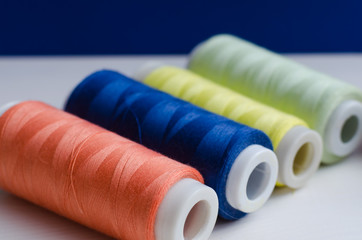 Close-up of various colored spools of sewing thread lie on a wooden table
