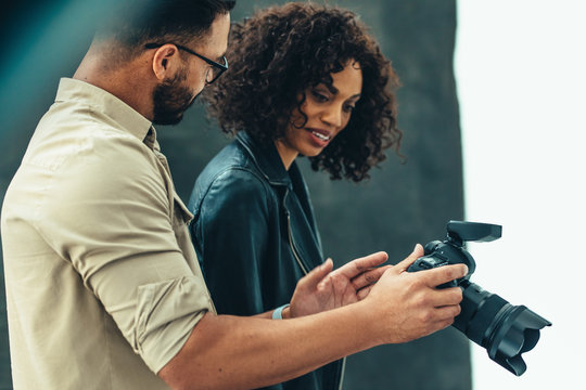Side view of a photographer showing image in his camera to a mod