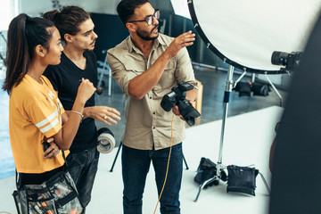 Photographer working with his team during a photo shoot in a stu