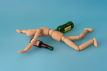 wooden man with many empty beer bottles. concept of alcoholism