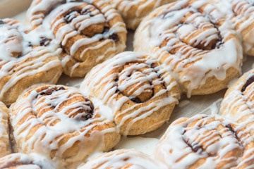 Pan of vegan whole-wheat homemade cinnamon raisin rolls drizzled with vanilla frosting