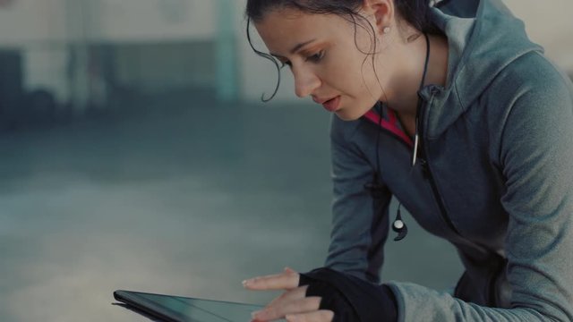 fitness woman athlete using tablet computer viewing performance results browsing charts on mobile device screen enjoying exercise goal resting in fitness gym