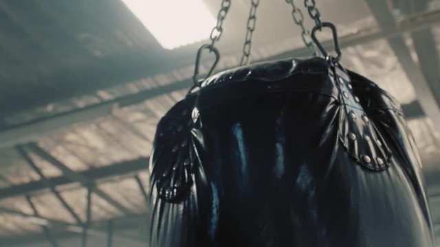 punching bag hanging in kickboxing fitness gym swinging motion close up
