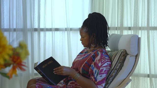 A lovely African American woman smiles softly and seems encouraged after reading her Bible and being in prayer.