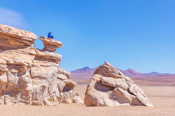 Homme assis sur un rocher dans le désert de sel de Uyuni en Bolivie Paysage voyage aventure