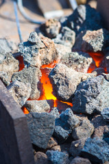 blacksmith furnace with burning coals, tools, and glowing hot metal workpieces
