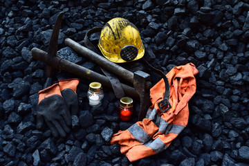 Vigil light, candle with the miner belongings (helmet, gloves, pickaxe, vest, belt) - obrazy, fototapety, plakaty