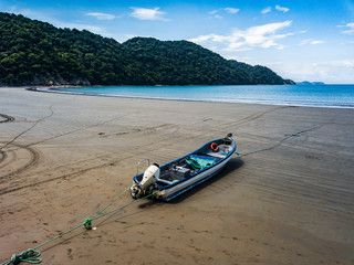 A lone fishermans colorful motor boat sits moored on a beach at low tide on an empty Costa Rican Beach