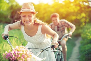 Happy young couple cycling through park