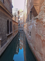 Alley canal with building reflection in water of Venice