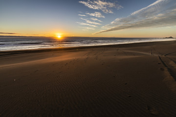 Amazing orange sunset over the sand dunes making very nice shadows in front of the Pacific Ocean at 
