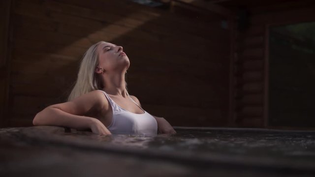 Sexy girl enjoying jacuzzi outdoors. Sexy woman enjoying spa outdoor. Blonde girl relaxing in jacuzzi poll. Spa procedures in hot pool outside