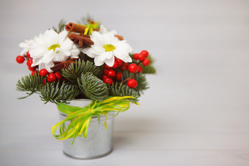 Christmas bouquet of flowers of red, yellow color with cones with fruit tangerines on a white wooden background.