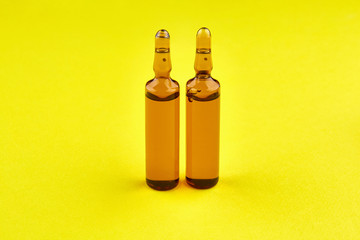 Brown ampoules with medicine on yellow background