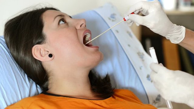Young woman at doctor being tested for pain in the throat