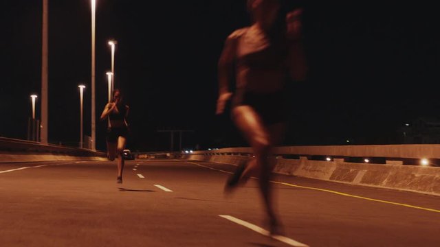athletic women running race competitive runners sprinting fast competition in late night urban city endurance challenge