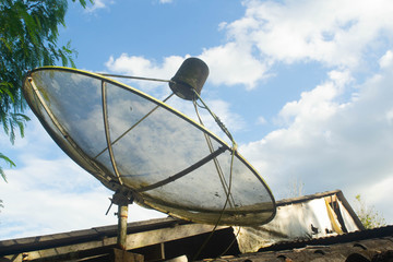 satellite dish on roof of house with blue sky and white cloud background