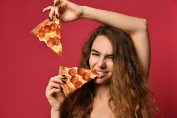 Young beautiful woman eating slice of pepperoni pizza on pink red