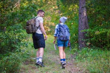 Young couple walking in the forest. Hiking concept in the mountain in summer